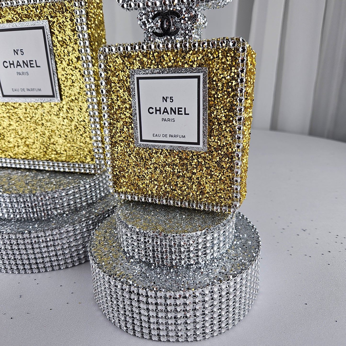 gold chanel birthday decorations Close up glitter detail on gold and silver Chanel perfume bottle centerpiece for upscale birthday party decor