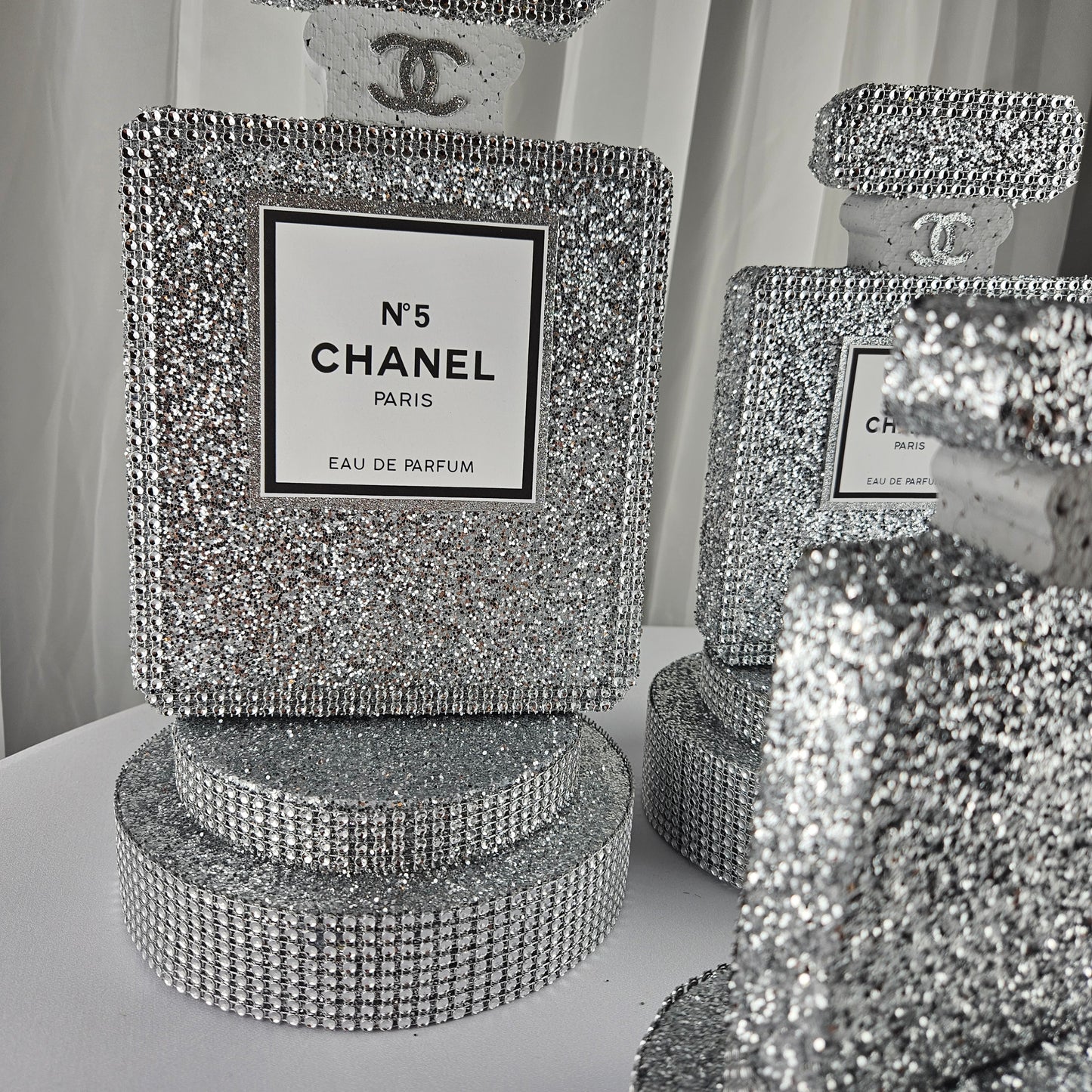 Angled view of Chanel inspired silver perfume centerpiece for glam party decor
