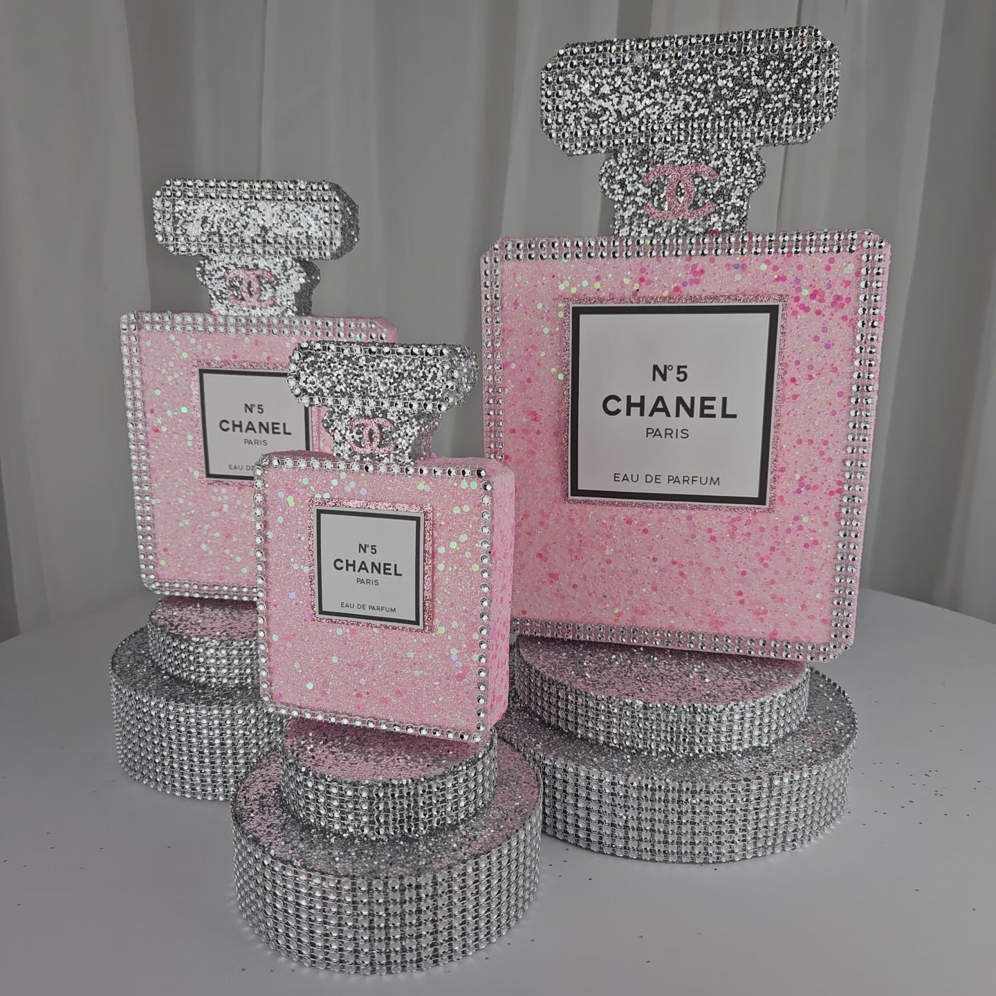 Front view of pink and silver Chanel inspired perfume centerpiece for luxury birthday decorations

