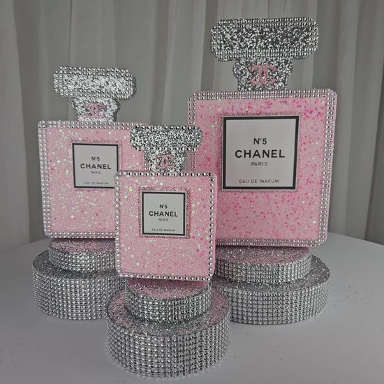 Angled view of Chanel inspired pink and silver perfume centerpiece for glam party decor

