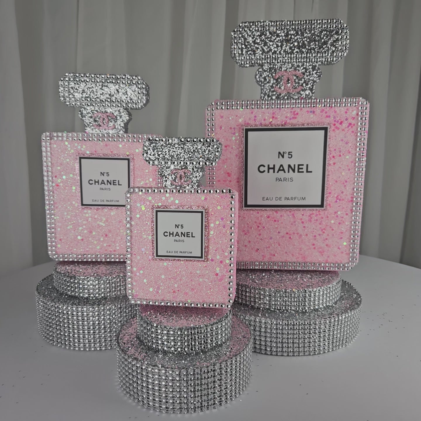 Angled view of Chanel inspired pink and silver perfume centerpiece for glam party decor

