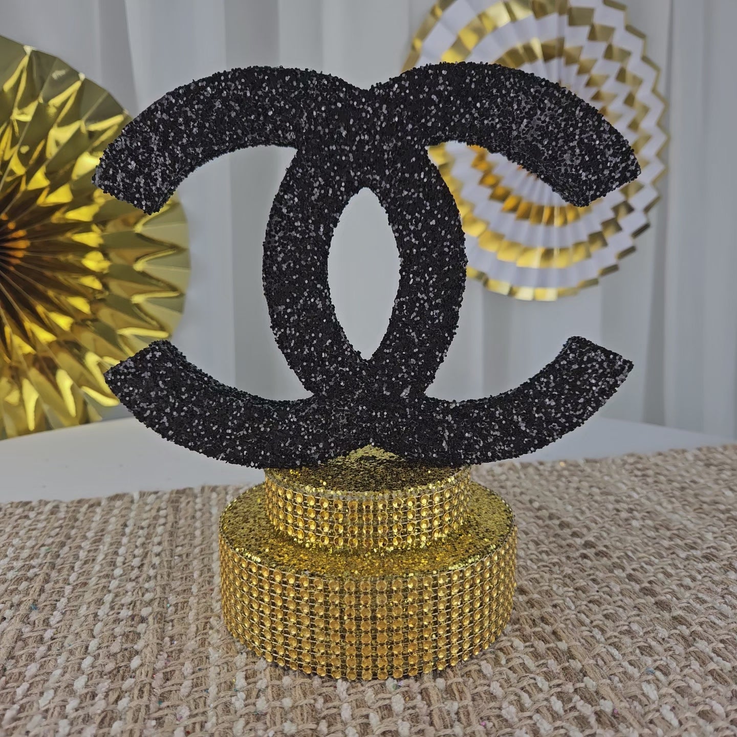 Luxury Chanel party centerpiece with black glitter and gold base
